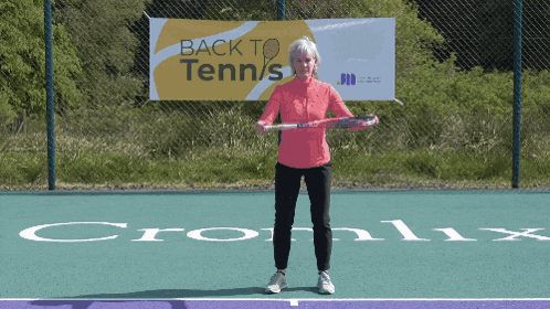 a woman holds a tennis racquet in front of a back to tennis banner