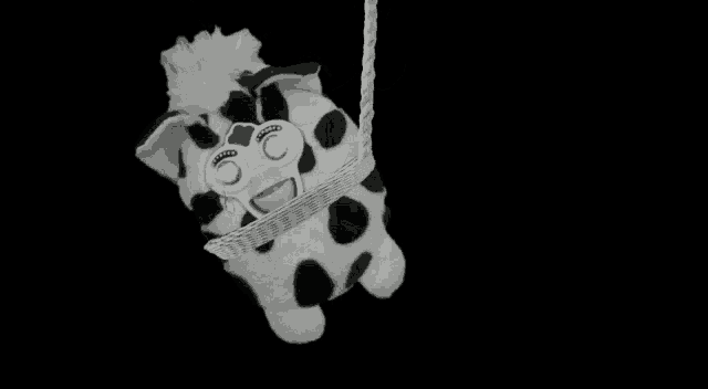 a black and white photo of a stuffed animal tied up with a rope .