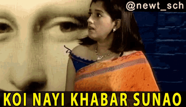 a woman in an orange saree is standing in front of a painting of a man 's face