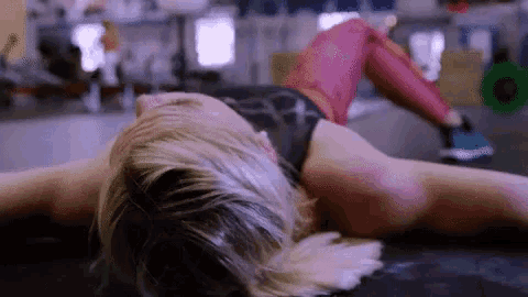 a woman is laying on her stomach in a gym with her legs crossed .