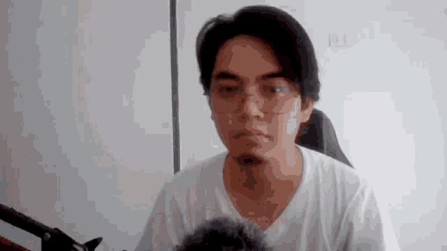 a man wearing glasses and a white shirt is making a funny face .