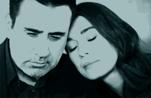 a man and a woman are posing for a picture with their eyes closed .