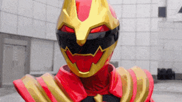a close up of a red and gold superhero wearing a helmet and a red cape .