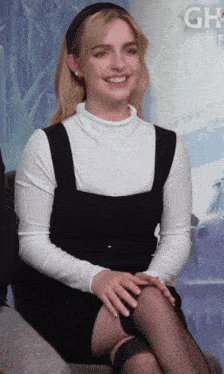 a woman sits in front of a poster that says gh
