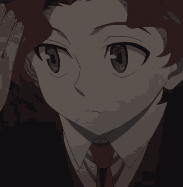 a boy with red hair and green eyes is wearing a black suit and red tie