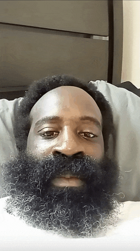 a man with a large beard is laying on a bed
