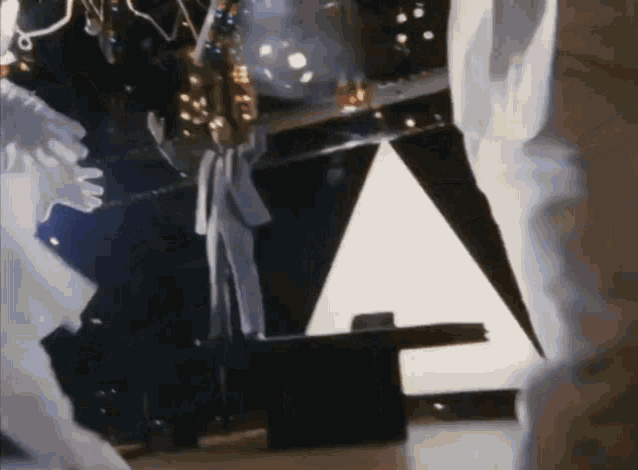 a close up of a person standing on a stage in front of a pyramid .