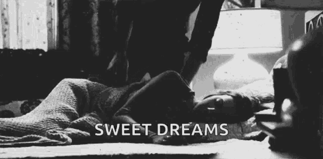 a black and white photo of a woman laying on a bed with the words `` sweet dreams '' written on the bottom .