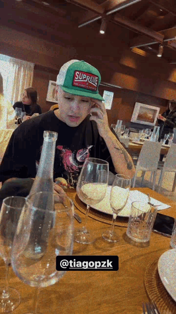 a man wearing a green hat that says supreme on it