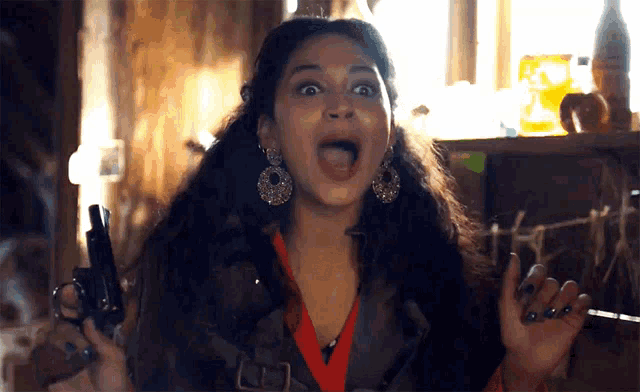 a woman is holding a gun with her mouth wide open
