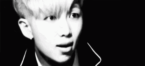 a black and white photo of a young boy smiling in a dark room .