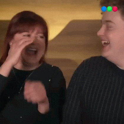 a man and a woman are laughing together and the woman is covering her face .