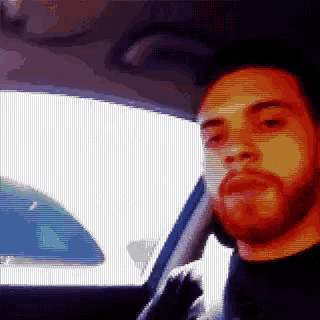 a pixelated image of a man with a beard in a car