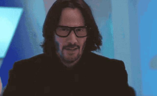 a man with long hair wearing glasses and a black jacket