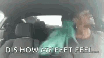 a man is sitting in the back seat of a car with his feet up .