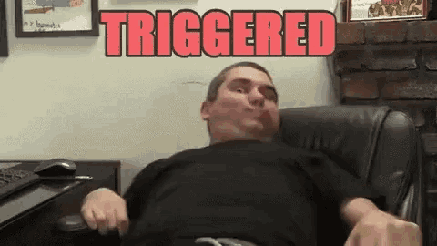 a man in a black shirt is sitting in a chair with the word triggered above him .