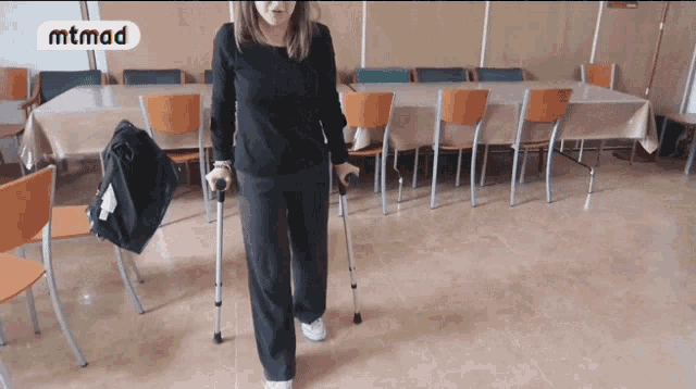 a woman with crutches stands in front of a table with a mtmad logo on it