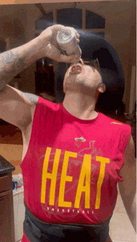 a man wearing a red heat basketball jersey drinks from a bottle