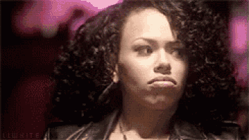 a woman with curly hair is making a funny face while wearing a leather jacket .