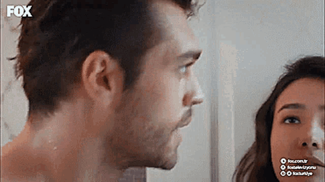 a man and a woman are looking at each other in a mirror .