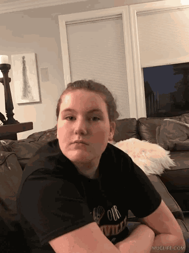 a girl is sitting on a couch wearing a black shirt that says " our will "