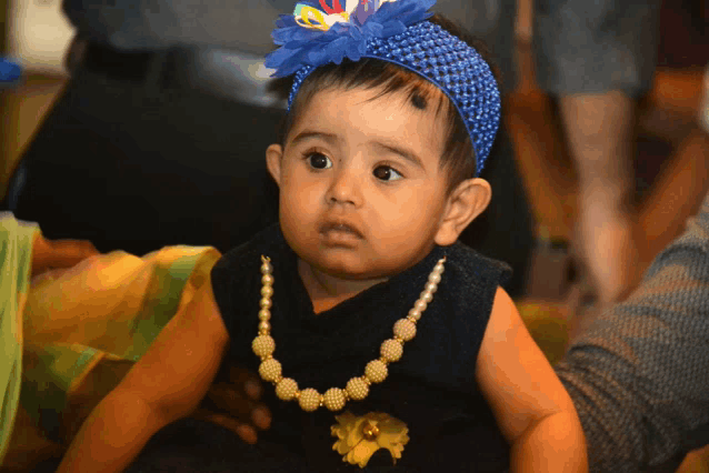 a little girl wearing a blue headband and a necklace
