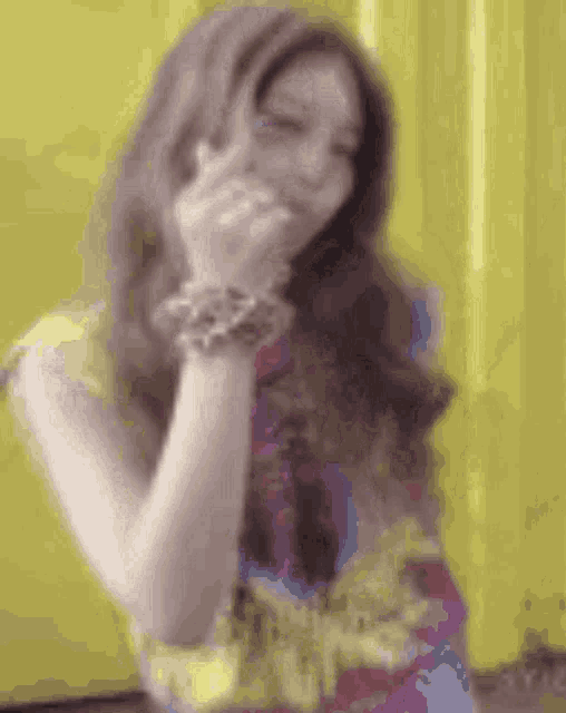 a woman is covering her mouth with her hand and wearing a bracelet .
