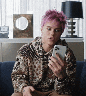 a young man with pink hair is looking at his phone
