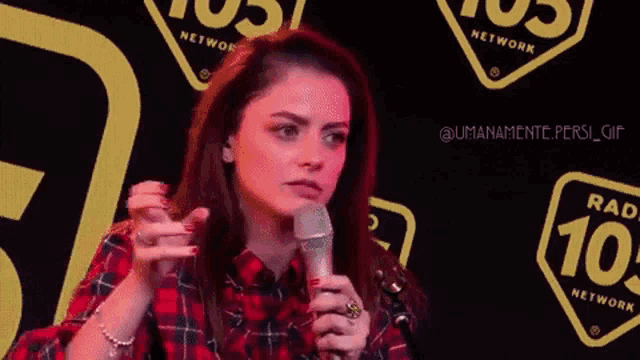 a woman in a plaid shirt is holding a microphone and saying puo ' dari
