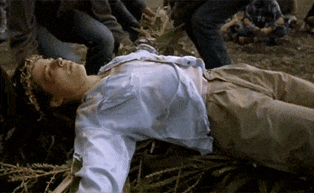 a woman in a blue shirt is laying on the ground with her arms outstretched
