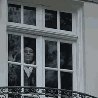 a man is looking out of a window of a building .