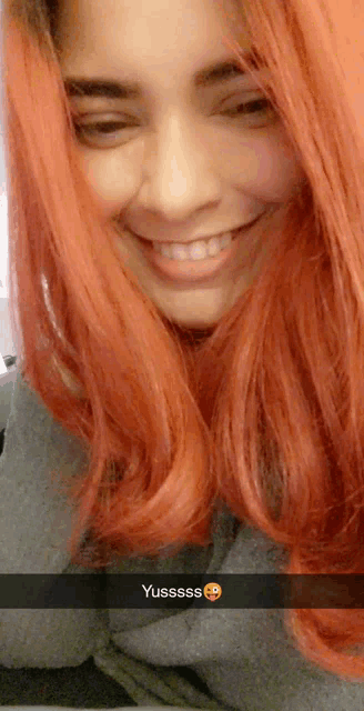 a woman with red hair is smiling with a snapchat sticker that says yussss
