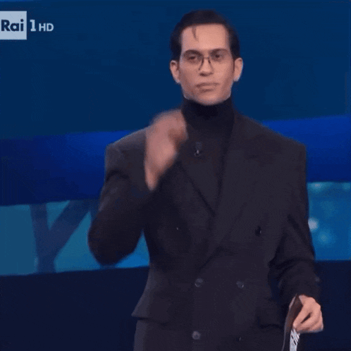 a man in a suit and turtleneck is holding a magazine that says rai 1 hd on it