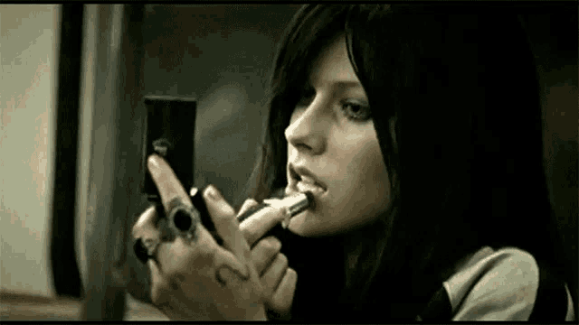 a woman is applying lipstick in front of a mirror with the number 2 on her hand