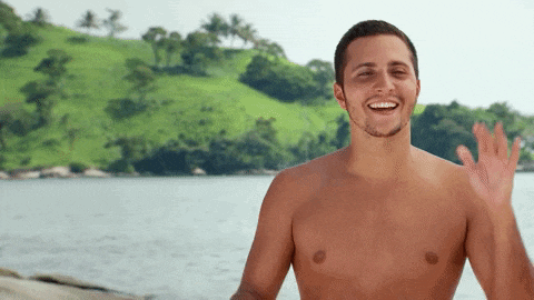 a shirtless man is smiling and waving at the camera on the beach