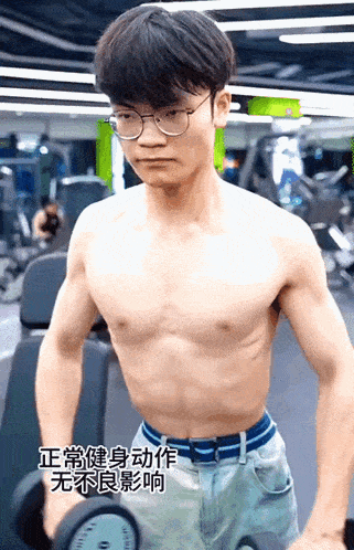 a man without a shirt is lifting a dumbbell in a gym