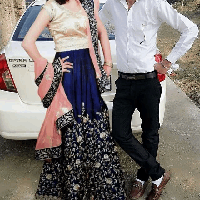 a man and a woman are posing in front of an optra l car