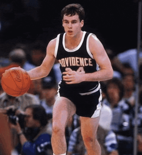 a basketball player wearing a providence jersey dribbles the ball