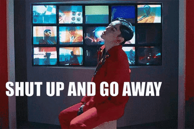 a man in a red suit is sitting in front of a screen that says shut up and go away ..