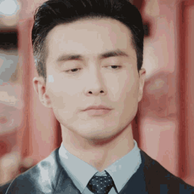 a man wearing a suit and tie looks down at something