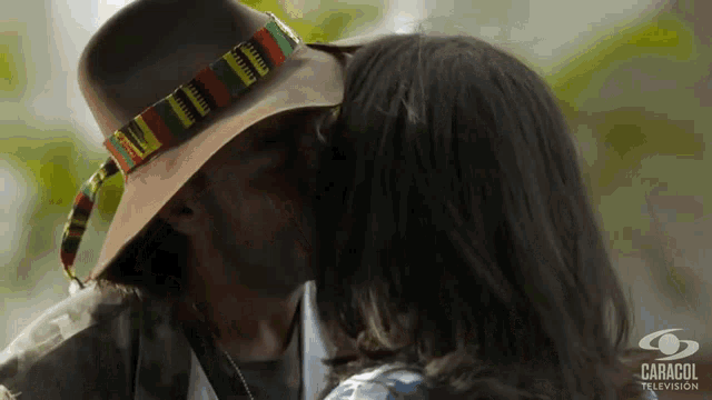 a man wearing a cowboy hat kisses a woman on the cheek
