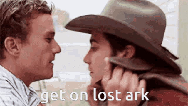 a man in a cowboy hat is kissing another man .