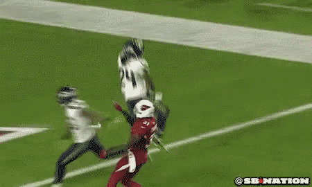a football player in a red jersey is being tackled by another player on a field .