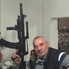 a man is holding a gun in front of a wall in a room .
