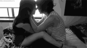 a couple kissing on a bed with a poster of harry potter on the wall