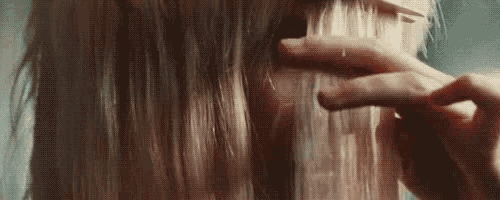 a woman is brushing her hair with a brush in a close up of her face .