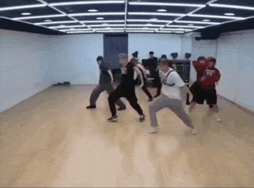 a group of people are dancing in a room with a wooden floor .
