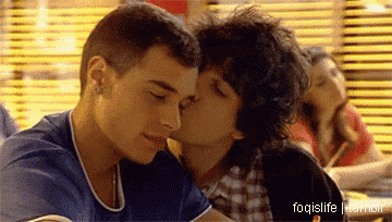 a man kissing another man on the cheek in a restaurant