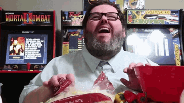 a man is laughing in front of a mortal kombat arcade game
