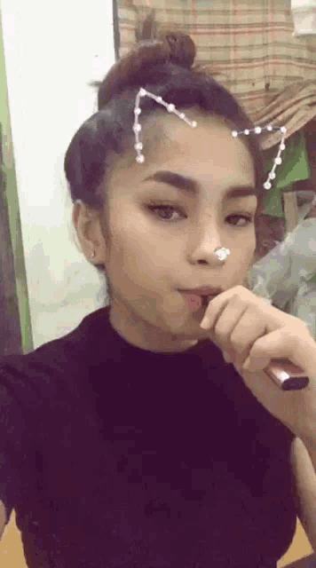 a woman with a cat ear on her head is smoking an electronic cigarette .